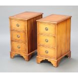 A pair of Georgian style crossbanded yew bedside chests of 3 drawers, raised on bracket feet 63cm
