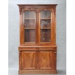 A Victorian mahogany bookcase on cabinet with moulded cornice, fitted adjustable shelves enclosed by