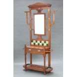 An Edwardian Art Nouveau walnut hall stand with rectangular bevelled mirror to the centre, the