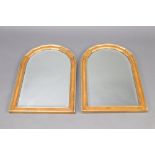 A pair of 19th Century style arched bevelled plate mirrors contained in walnut and gilt painted