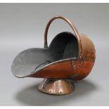 A Victorian copper helmet shaped coal scuttle raised on a circular base 33cm x 41cm x 28cm