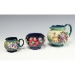 A William Moorcroft green ground jug decorated Spring flowers pattern 13cm, a smaller Moorcroft vase