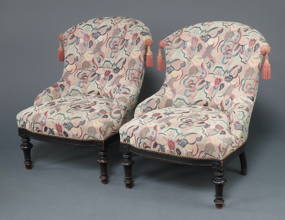 A pair of Victorian mahogany tub back chairs upholstered in pink and blue material, raised on turned