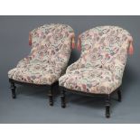 A pair of Victorian mahogany tub back chairs upholstered in pink and blue material, raised on turned