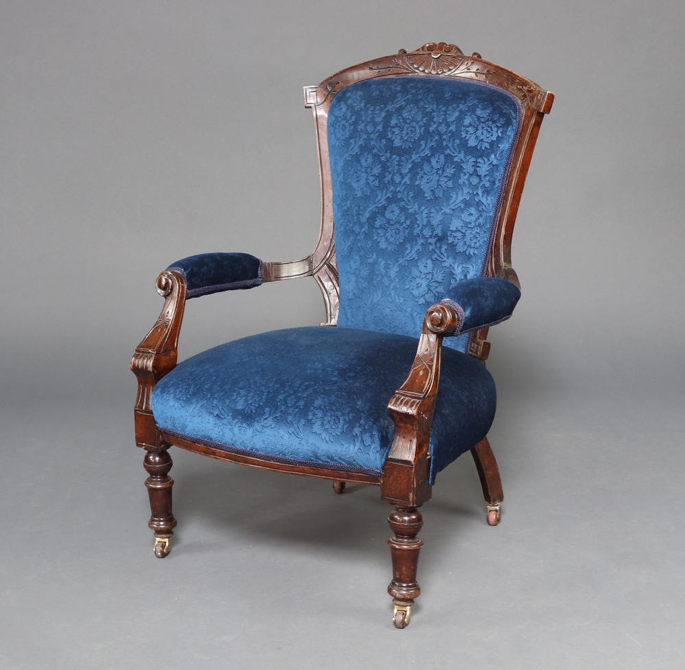 A Victorian carved mahogany open armchair upholstered in blue material raised on turned supports