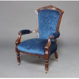 A Victorian carved mahogany open armchair upholstered in blue material raised on turned supports