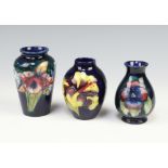 A Moorcroft blue ground baluster vase decorated pansies 9cm, ditto orchid pattern 10cm and another