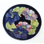 A Walter Moorcroft blue ground plate decorated clematis pattern, monogrammed and with paper label