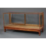 A 1930's oak and plate glass shop display cabinet 92cm h x 178cm w x 59cm d, raised on square