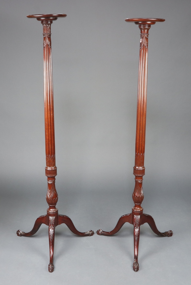 A near pair of Edwardian Chippendale style turned and reeded mahogany torcheres, raised on a