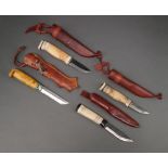 Three Swedish skinning knives with wooden grips and leather scabbards together with 1 other with a