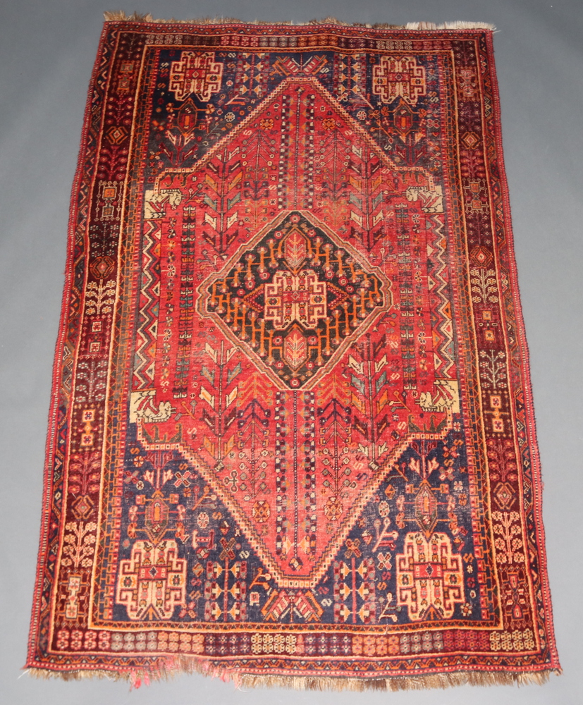 A red, blue, orange and black ground Afghan rug with central medallion within a multi row border