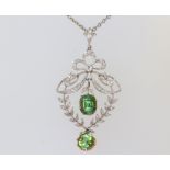 An Edwardian white and yellow metal diamond and peridot drop pendant with bow crest on a plated
