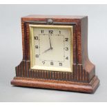 An Art Deco timepiece with 11cm square silvered dial, Roman numerals, contained in an oak case