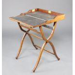 An Edwardian mahogany campaign style folding writing table raised on X framed supports with turned