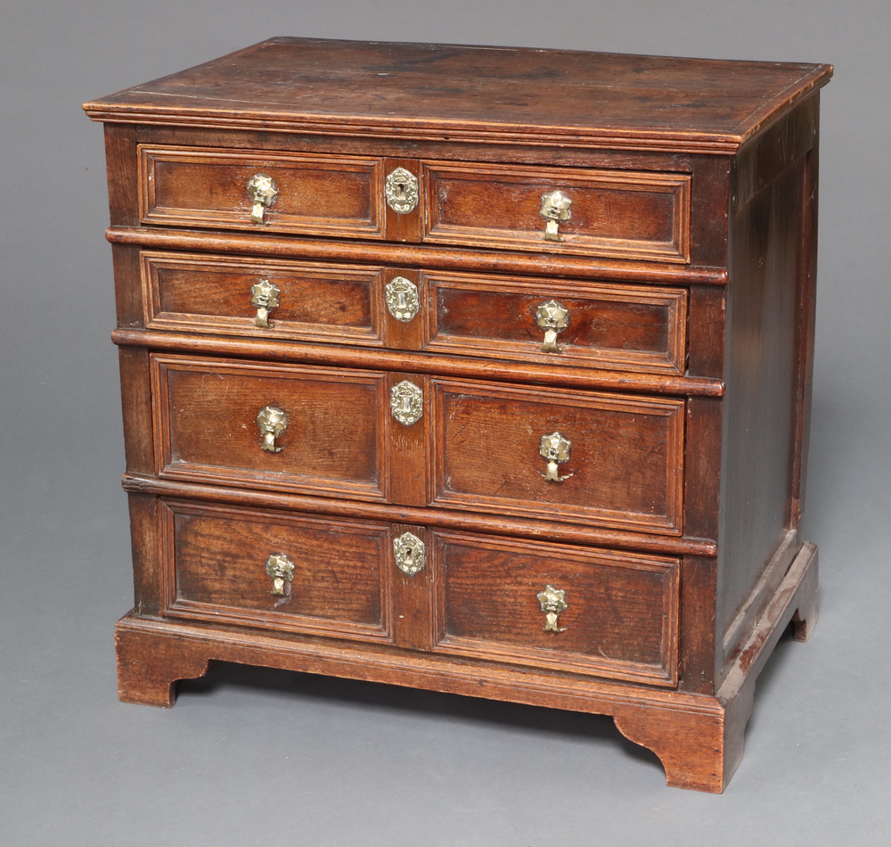 A Queen Anne oak chest of 4 long drawers with original brass pin drop handles, crowned brass