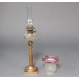 A reeded gilt metal oil lamp with Corinthian column and faceted glass reservoir, chimney and red