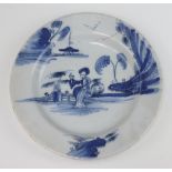 An 18th Century Delft blue and white plate decorated with a seated lady with pavilion in the