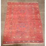 A red and white ground Afghan rug with 2 stylised medallions to the centre within a multi row border