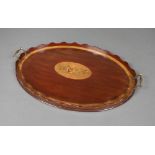 An Edwardian oval inlaid mahogany twin handled tea tray with wavy border and central inlaid floral