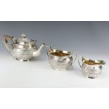 A Victorian repousse silver tea set comprising teapot, sugar bowl and milk jug decorated with