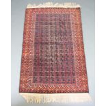 A blue, black, red and orange ground Belouche rug with central field formed of squares within a