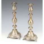 A pair of Continental white metal repousse waisted candlesticks decorated with flowers and fruits