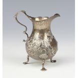 A Georgian silver repousse cream jug with shell knees and pad feet, rubbed marks, 75 grams