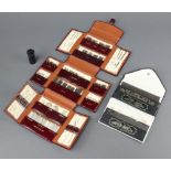 A Cranberry pin case containing various sewing needles in a red leather needle case together with