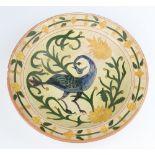 A Della Robbia pottery deep bowl, decorated with a stylised bird amongst flowers, incised mark to