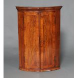 A Georgian inlaid walnut bow front hanging corner cabinet with moulded cornice, fitted shelves