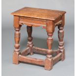 An 18th/19th Century oak joined stool raised on cup and cover supports with box framed stretcher