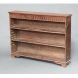 An Ipswich style bleached oak bookcase with arcaded decoration fitted adjustable shelves, raised
