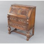 An Edwardian carved oak bureau, the fall front revealing a well fitted interior above 2 drawers,