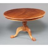 A Chippendale style circular mahogany pedestal dining table with gadrooned border, turned column and