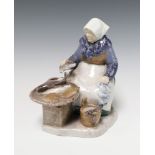 A Bing & Grondahl porcelain figure of a seated lady fishmonger, the base marked B&G 2233SA 20cm