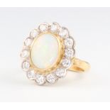 An 18ct yellow gold oval opal and diamond cluster ring, the opal 12mm x 10mm, the 14 brilliant cut