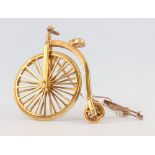 A yellow metal penny farthing brooch by Paul Eaton, 12.9 grams