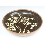 A slipware shallow bowl decorated with a stylised bird and impressed marks 26.5cm