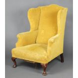 A Georgian style winged armchair upholstered in yellow material, raised on cabriole supports 108cm h