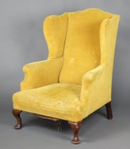 A Georgian style winged armchair upholstered in yellow material, raised on cabriole supports 108cm h