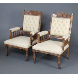 A pair of Victorian carved walnut open arm chairs upholstered in light buttoned material and