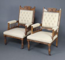 A pair of Victorian carved walnut open arm chairs upholstered in light buttoned material and