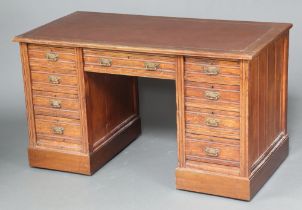 A Victorian oak desk with brown inset writing surface above 1 long and 8 short drawers with brass