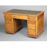 A Victorian light oak kneehole desk with green leather inset writing surface above 1 long and 8