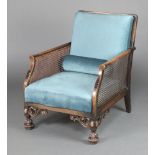 A 1930's beech framed single cane bergere armchair upholstered in blue material, raised on turned