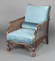 A 1930's beech framed single cane bergere armchair upholstered in blue material, raised on turned