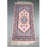 A pink and blue ground Afghan rug with stylised medallions to the centre 207cm x 100cm