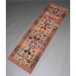 A rust ground Persian style machine made runner with stylised medallion to the centre 225cm x 75cm