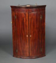 A Georgian inlaid mahogany bow front corner cabinet, shelved interior enclosed by panelled doors